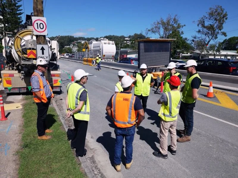 Traffic management team conducting roadwork site briefing beside active traffic control setup